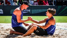 Szymon Beta i Artem Besarab (fot. Volleyball World) Na zdjęciu widzimy dwóch młodych polskich siatkarzy plażowych oraz ich trenera, stojących na podium w Puebli (Meksyk), gdzie odbywały się mistrzostwa świata U21. Zawodnicy w fioletowych koszulkach z napisem „POL” oraz numerami „1” i „2” dumnie prezentują srebrne medale oraz trofea. W tle tłum kibiców oraz międzynarodowe flagi, co podkreśla rangę wydarzenia. Na podium widnieje oznaczenie „2ND”, potwierdzające drugie miejsce Polaków w turnieju.