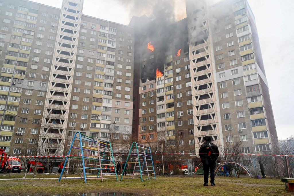 Праваахоўнік стаіць каля жылога дому, пашкоджанага ў выніку ракетнага абстрэлу Кіева, Украіна. 7 лютага 2024 года. (Фота: Sergei Supinsky / AFP / East News)